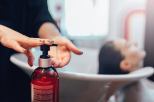 hairdresser shampooing a customer's hair with shampoo that contains citrus oils