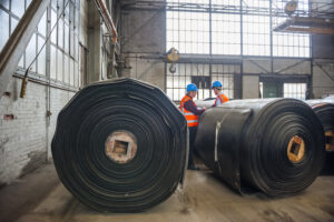 two factory workers inspecting rolls of rubber where citrus oils are being used in industrial applications